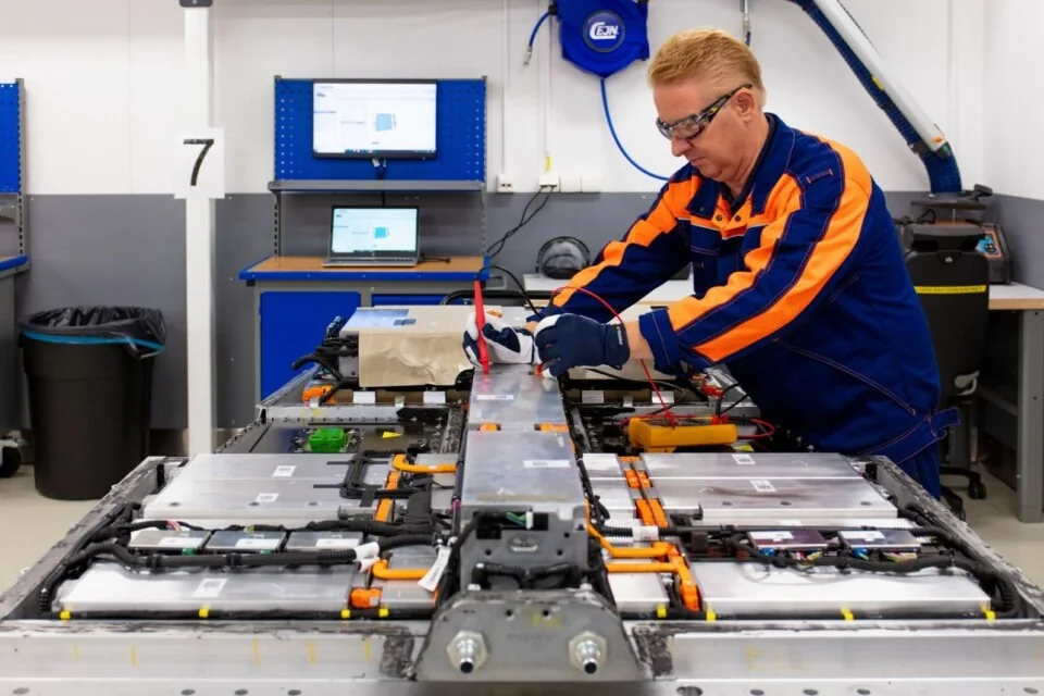 A technician inspecting EV battery modules in a workshop